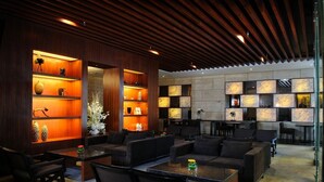 A modern lounge area with wooden paneling, built-in shelving with decorative items, and comfortable seating arrangements. - Tian Feng International Hotel (Shenyang)