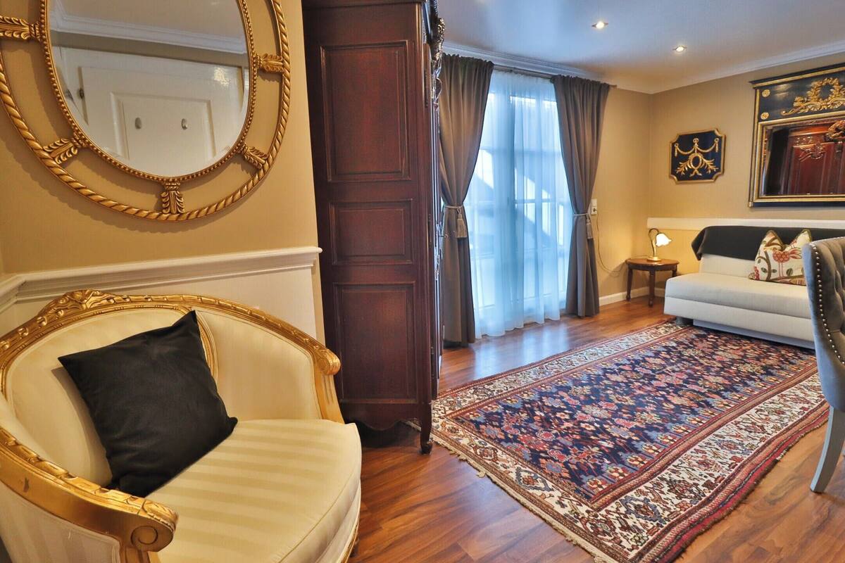 A room with a large mirror, a sofa, a patterned rug, and a wooden door.