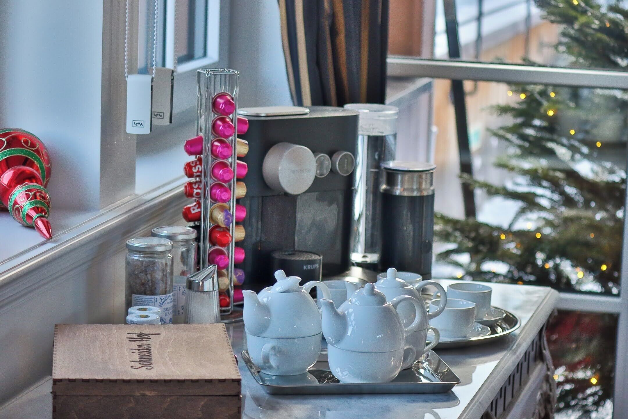 A kitchen counter with a coffee machine, teapots, cups, and a tray.