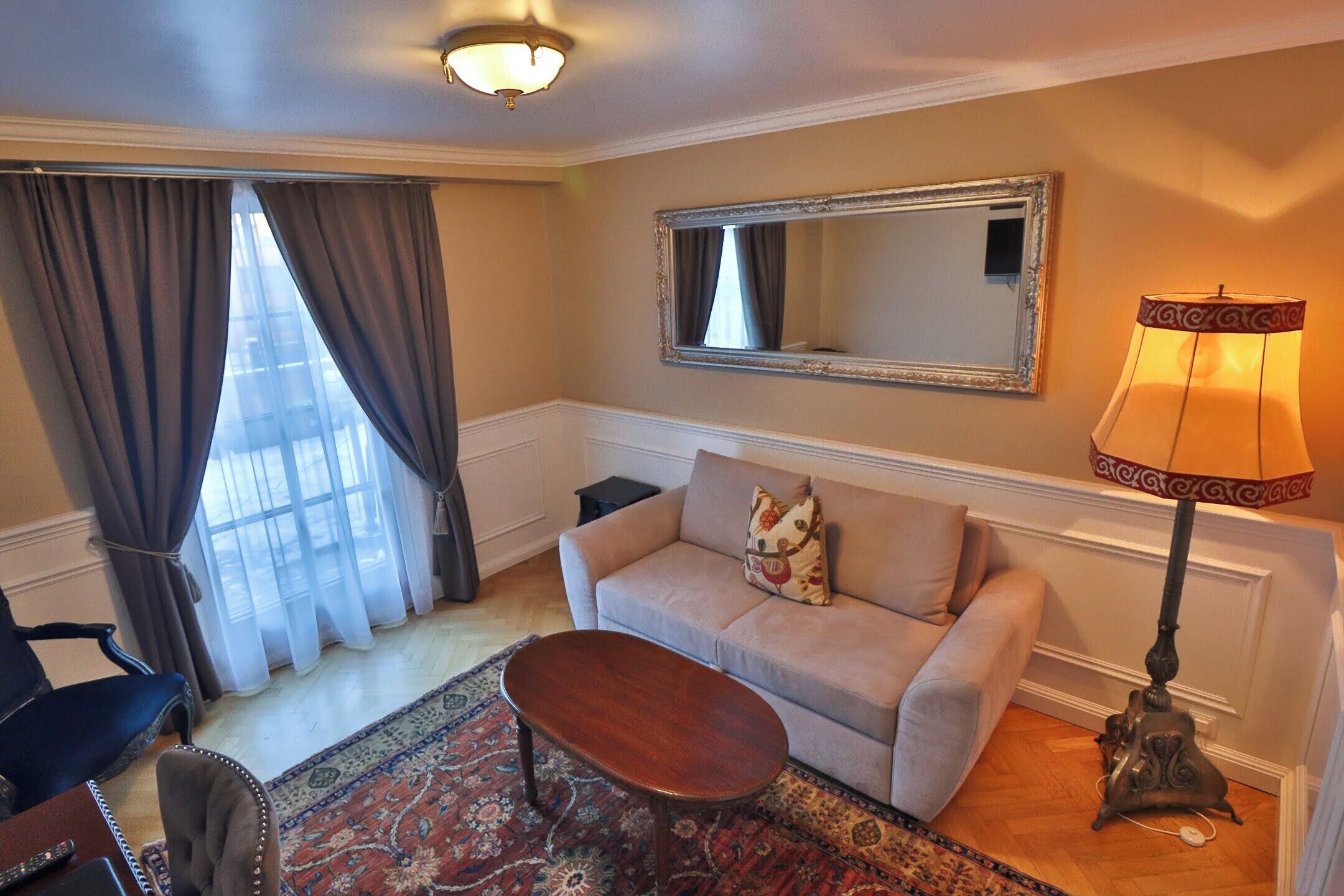 A living room with a sofa, a coffee table, a lamp, a chair, and a patterned rug.
