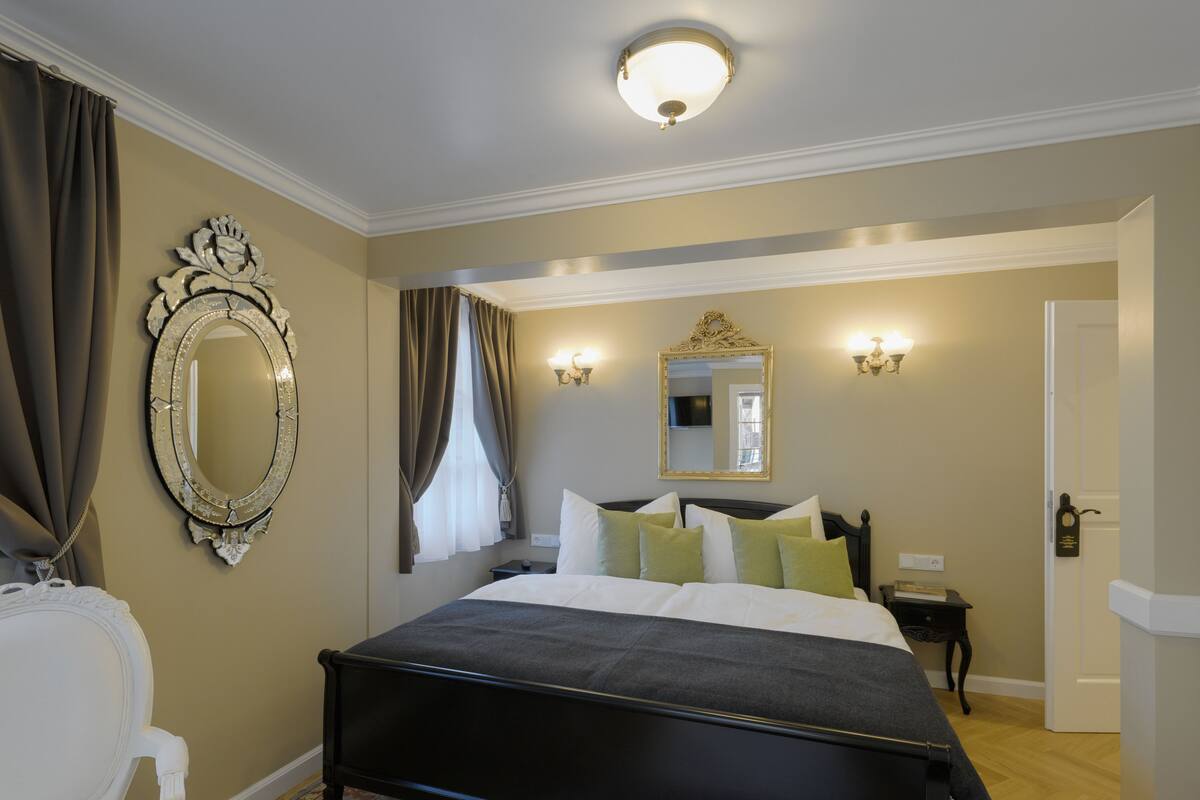 A bedroom with a large bed, a mirror, and two wall sconces.