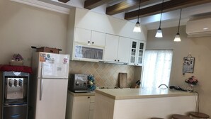 Una cocina con refrigerador, cafetera y taburetes de bar.