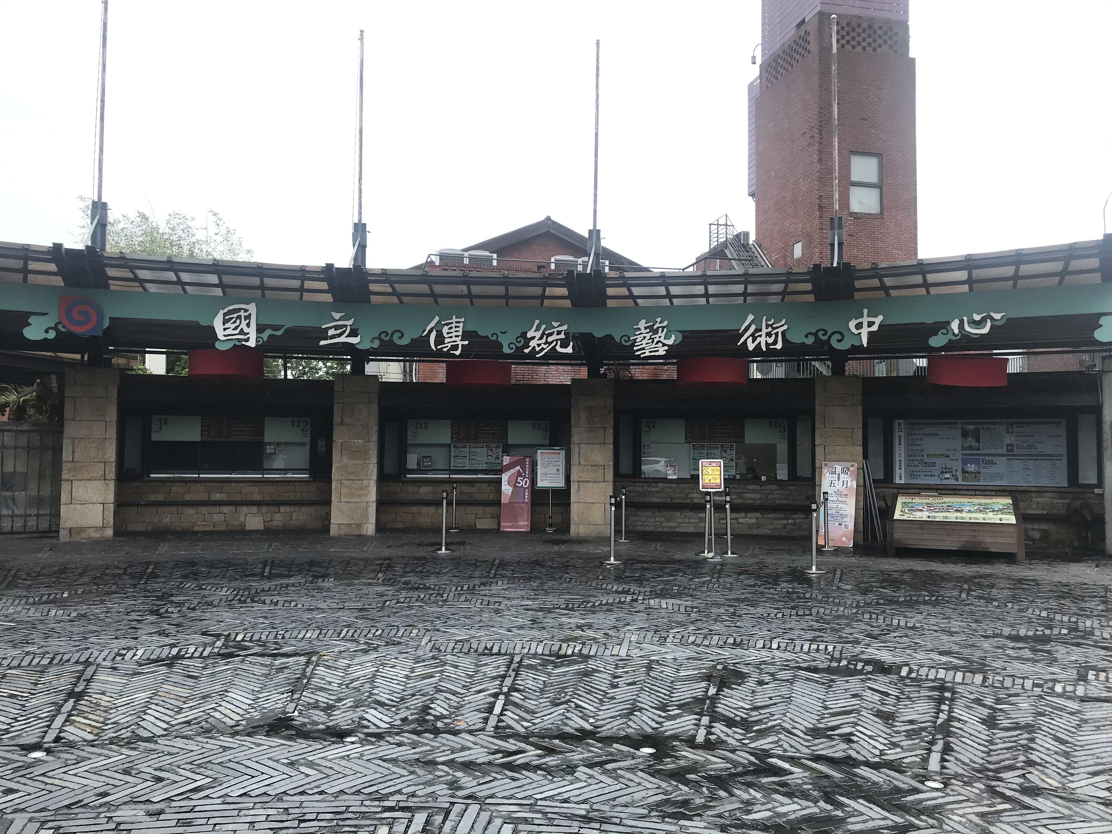 A building with a green awning and a brick facade. There are multiple windows and a signboard with text.