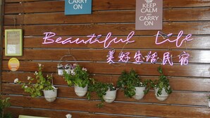 Pared de madera con plantas en macetas y dos letreros de neón que dicen "KEEP CALM AND CARRY ON".