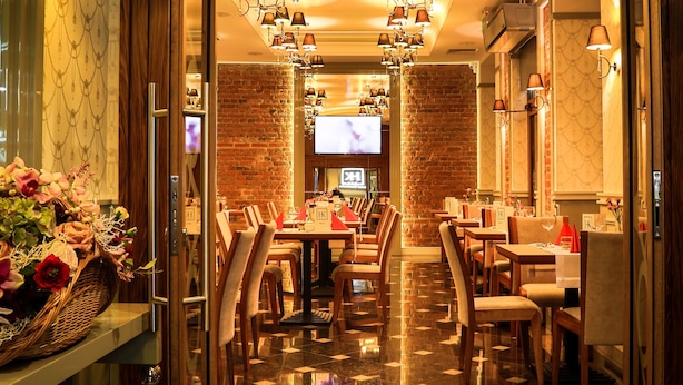 Un restaurante con pared de ladrillo, muebles de madera y una pantalla de televisión.