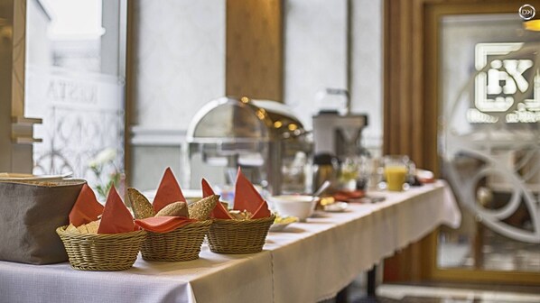 A buffet table with baskets of bread and a coffee station.
