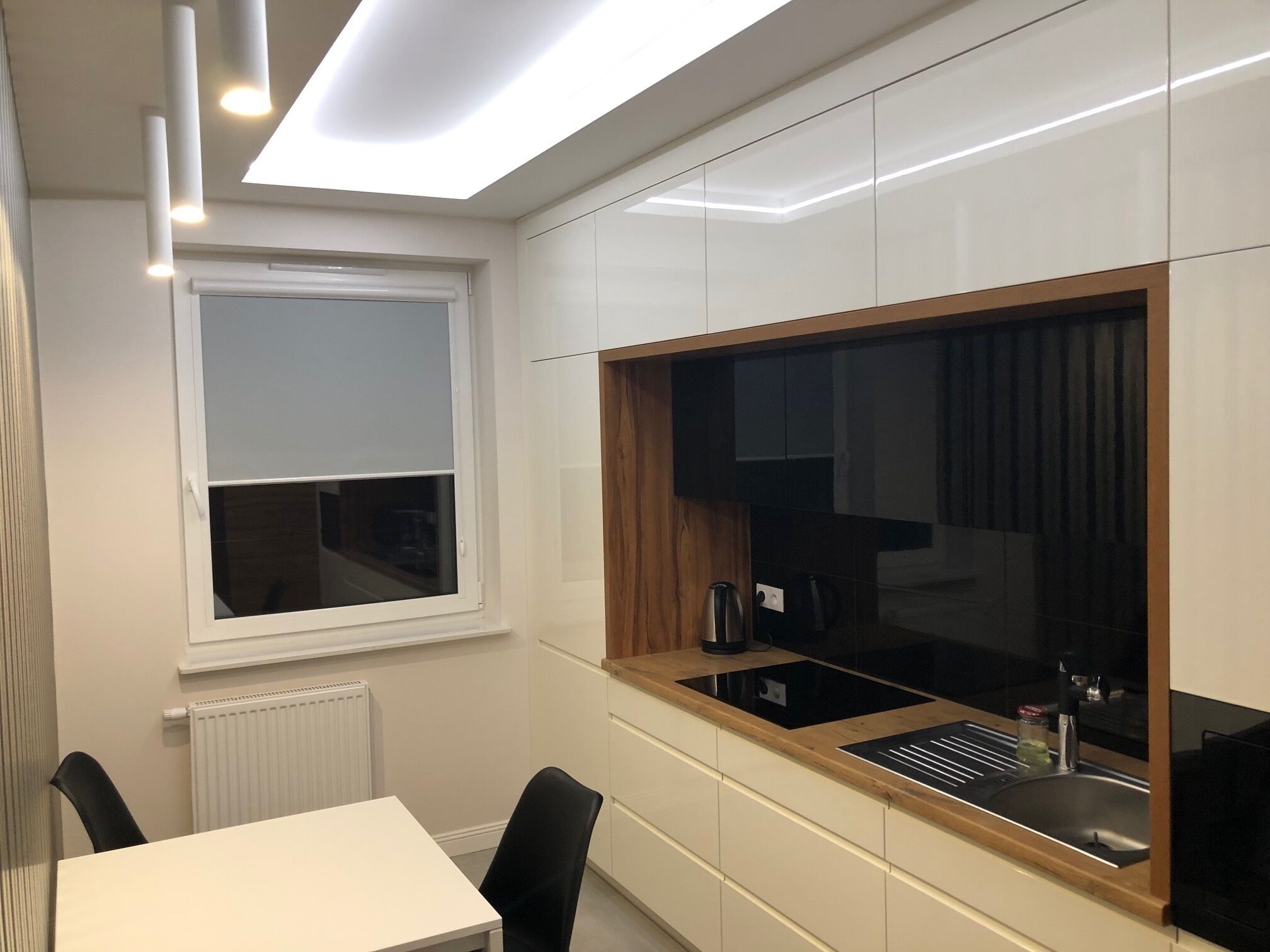 Een moderne keuken met een raam, een inbouwspoelbak en een wit aanrecht.