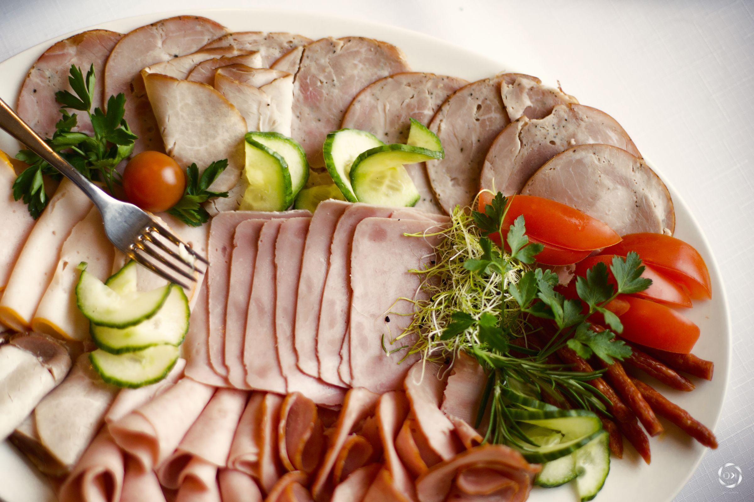 A platter of sliced meats and vegetables.