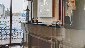 Zona de recepción con diseño moderno, que incluye un mostrador de recepción, un ventanal con vistas a la calle y un cartel con el nombre del hotel.
