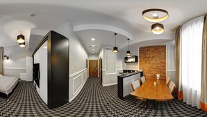 Habitación de hotel con piso a cuadros, una mesa de comedor de madera, una zona de cocina y una pared de acento de ladrillo.