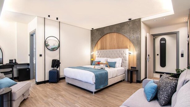 Una habitación de hotel moderna con una cama grande, un sofá, un escritorio y un armario.