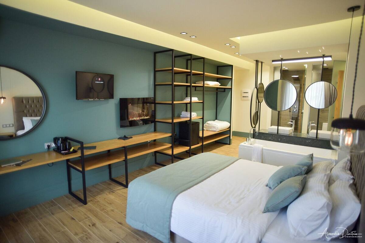 Une chambre moderne comprenant un lit, un bureau, une télévision, une bibliothèque et un grand miroir.