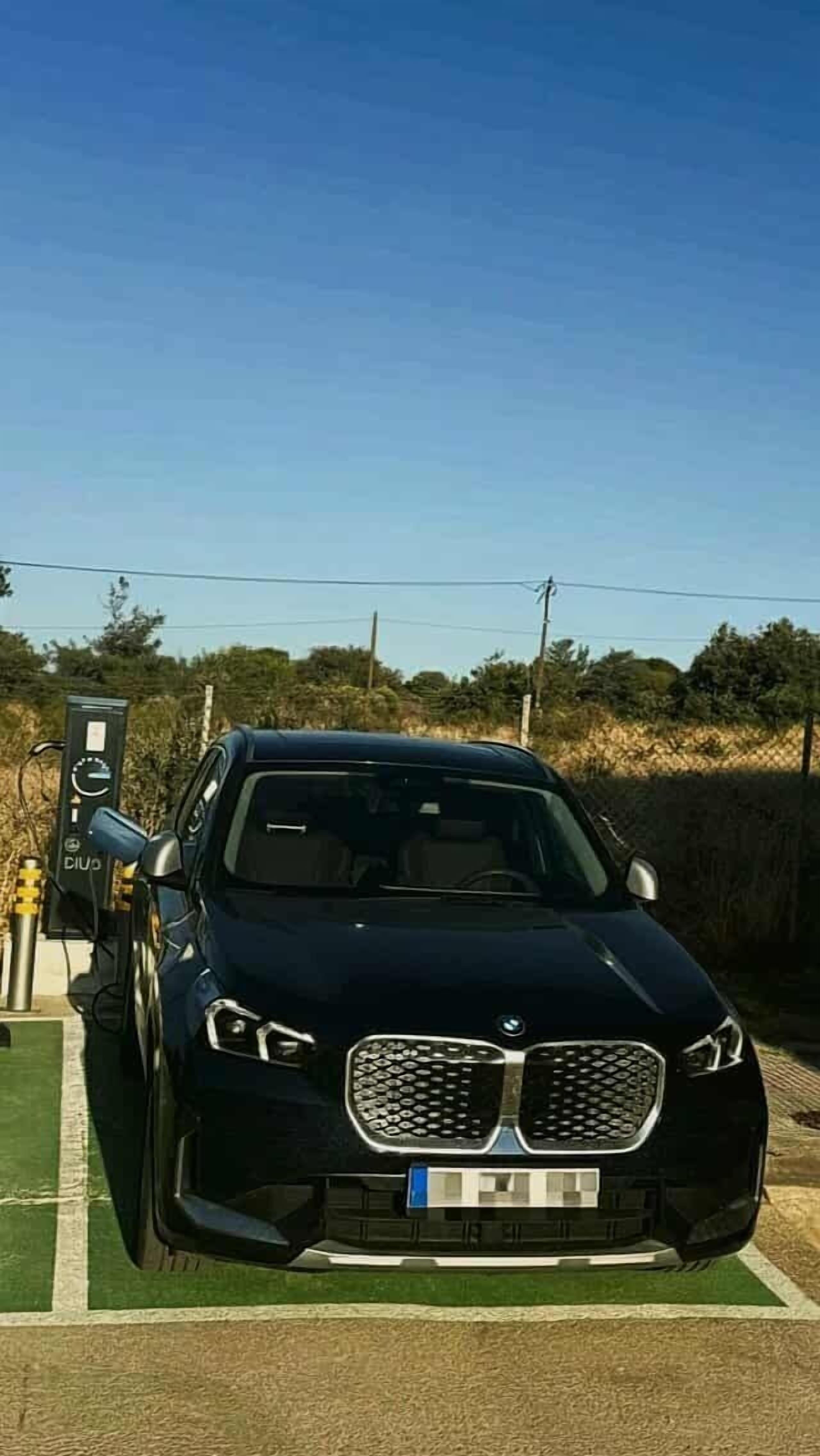 A black car parked at a charging station.