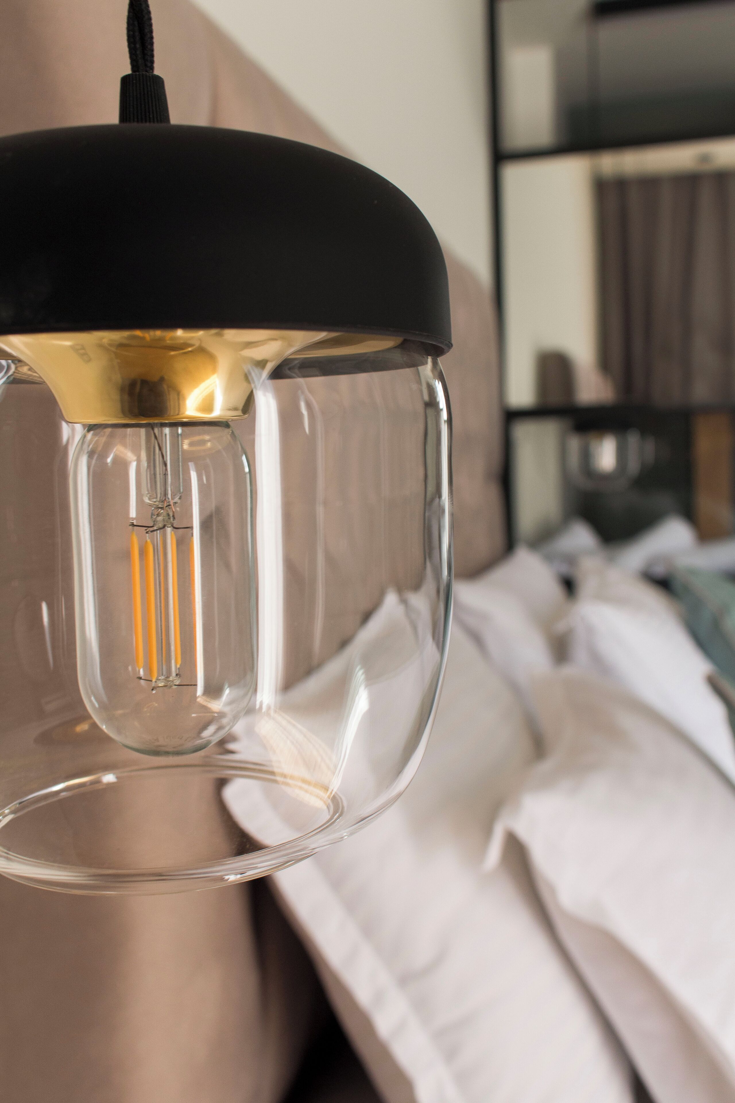 A clear glass pendant light fixture with a black shade, hanging from a ceiling.