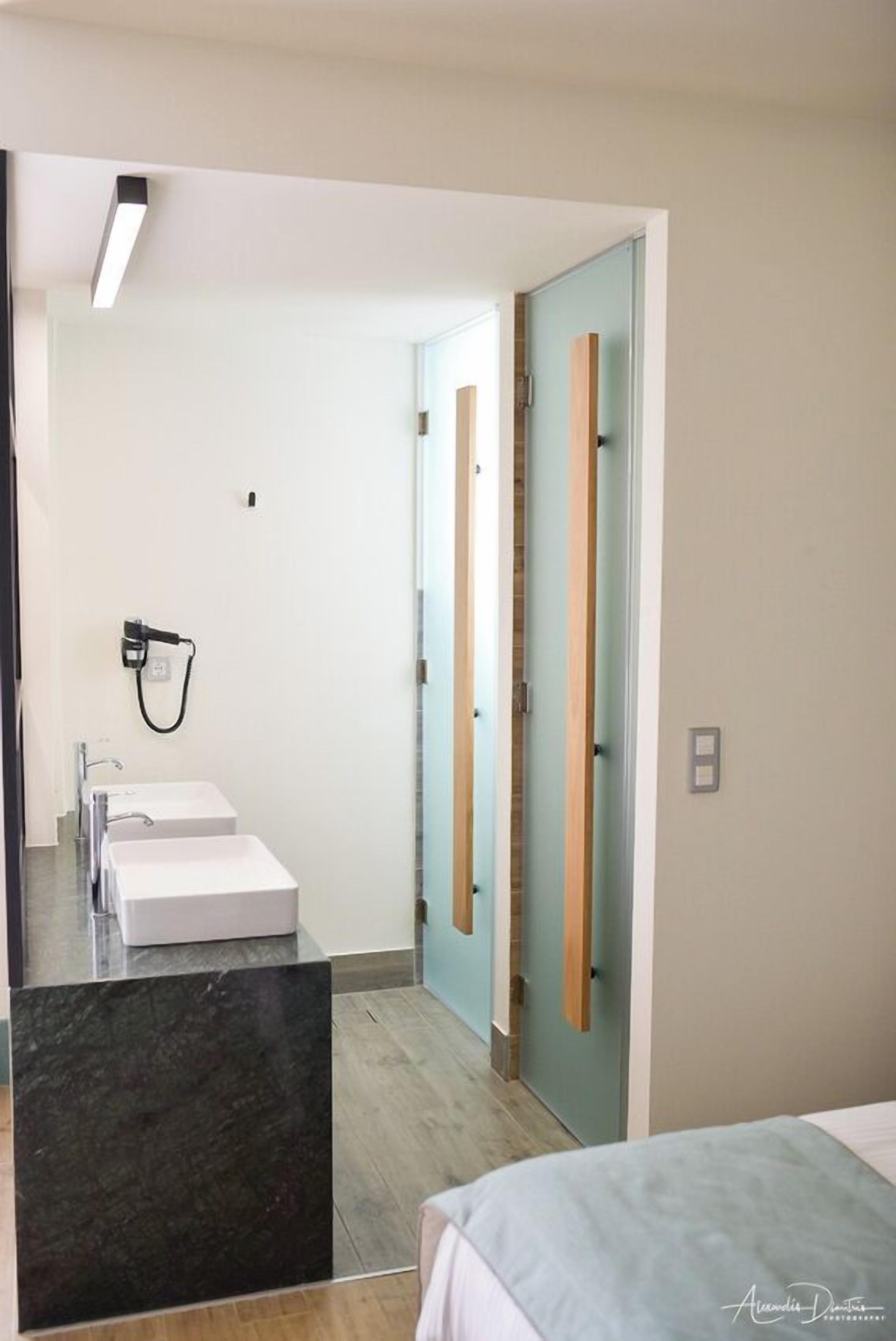 Une salle de bain moderne avec deux lavabos, un miroir et un espace douche.