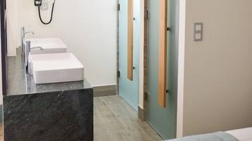 Une salle de bain moderne avec deux lavabos, un miroir et un espace douche.