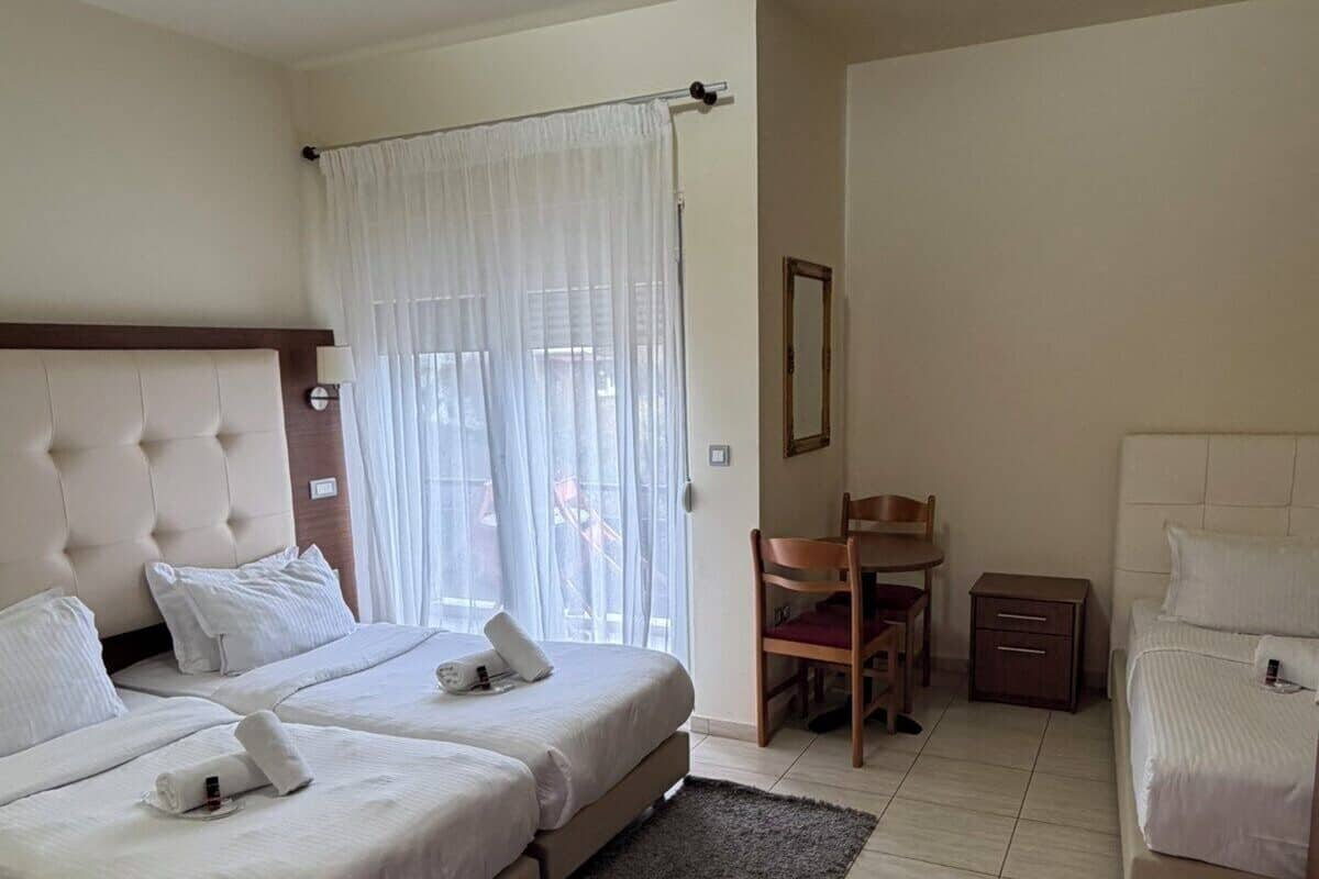 Une chambre d’hôtel avec deux lits, un bureau, une chaise et un miroir.