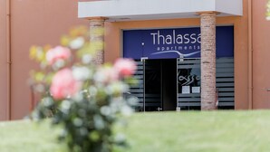 Un edificio con un letrero que dice "Thalassa Apartments" y una puerta de entrada grande.