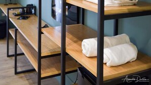 Una habitación de hotel con un banco de madera, un espejo montado en la pared y un estante con toallas dobladas.