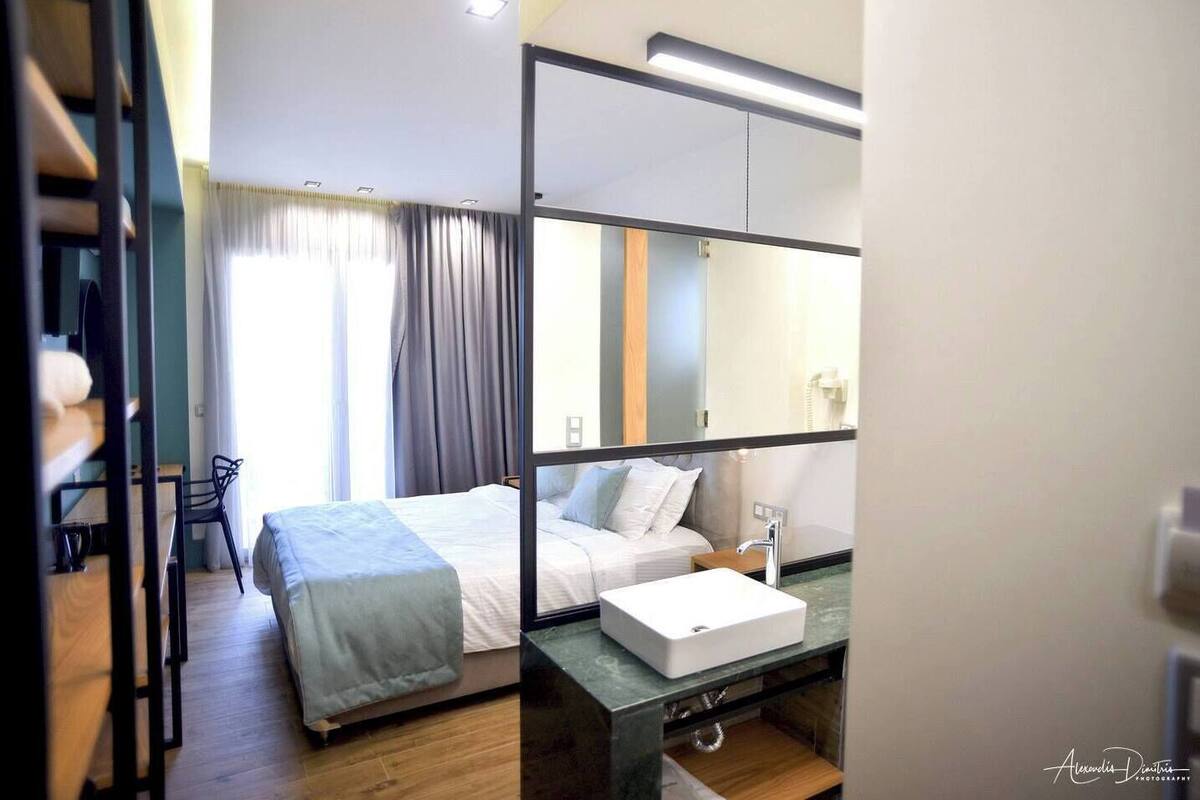 Une chambre d’hôtel moderne, équipée d’un lit, d’une table de chevet et d’un grand miroir.