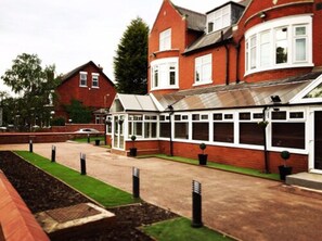 A red brick house with a conservatory. - Trivelles Mayfair (Stockport)