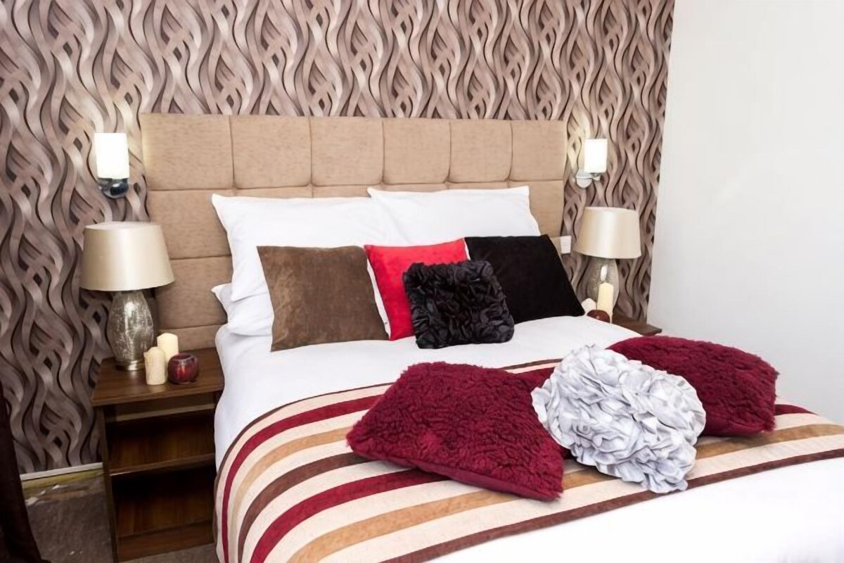 Une chambre d’hôtel avec une tête de lit à motifs, un lit avec une literie à rayures et deux lampes de chevet.
