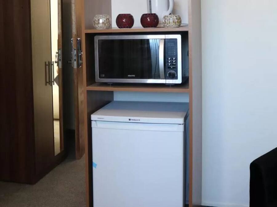 Uma kitchenette compacta com micro-ondas e mini-frigorífico.