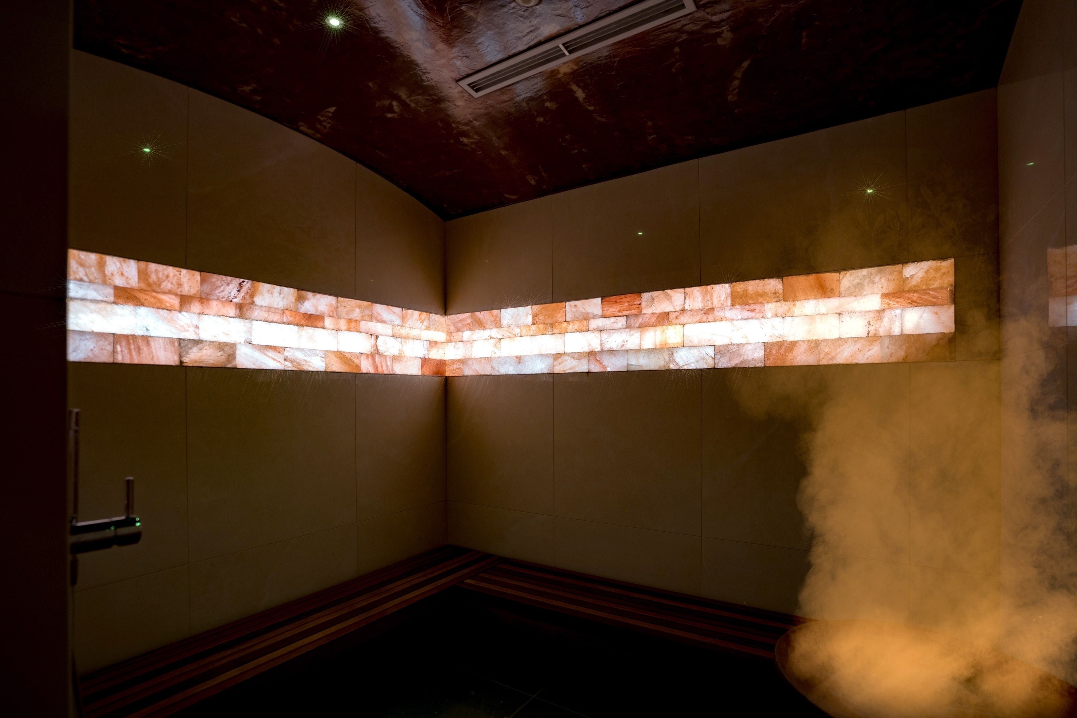 A steam room with a stone wall and a bench.