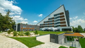 A modern hotel with a large patio area, outdoor seating, and a well-maintained garden. - Hotel Horizont Resort (Stara Lesna)