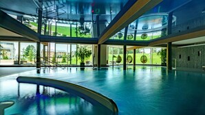 A spacious indoor swimming pool with clear glass walls and a view of the outdoors. - Hotel Horizont Resort (Stara Lesna)