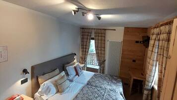 A bedroom with a bed, bedside table, and a window with curtains.