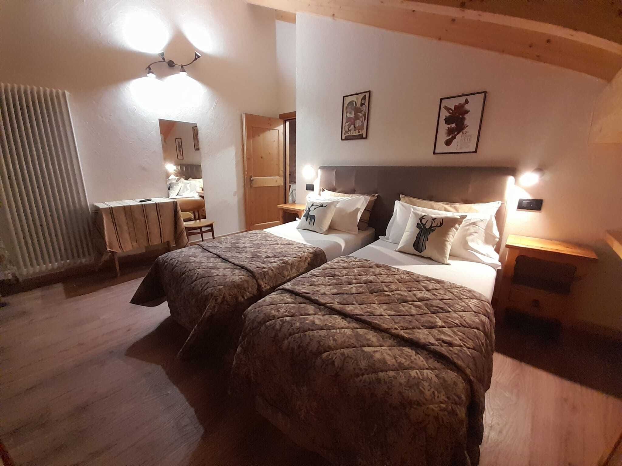 Habitación de hotel con dos camas, cabecero de madera y un escritorio pequeño con una silla.