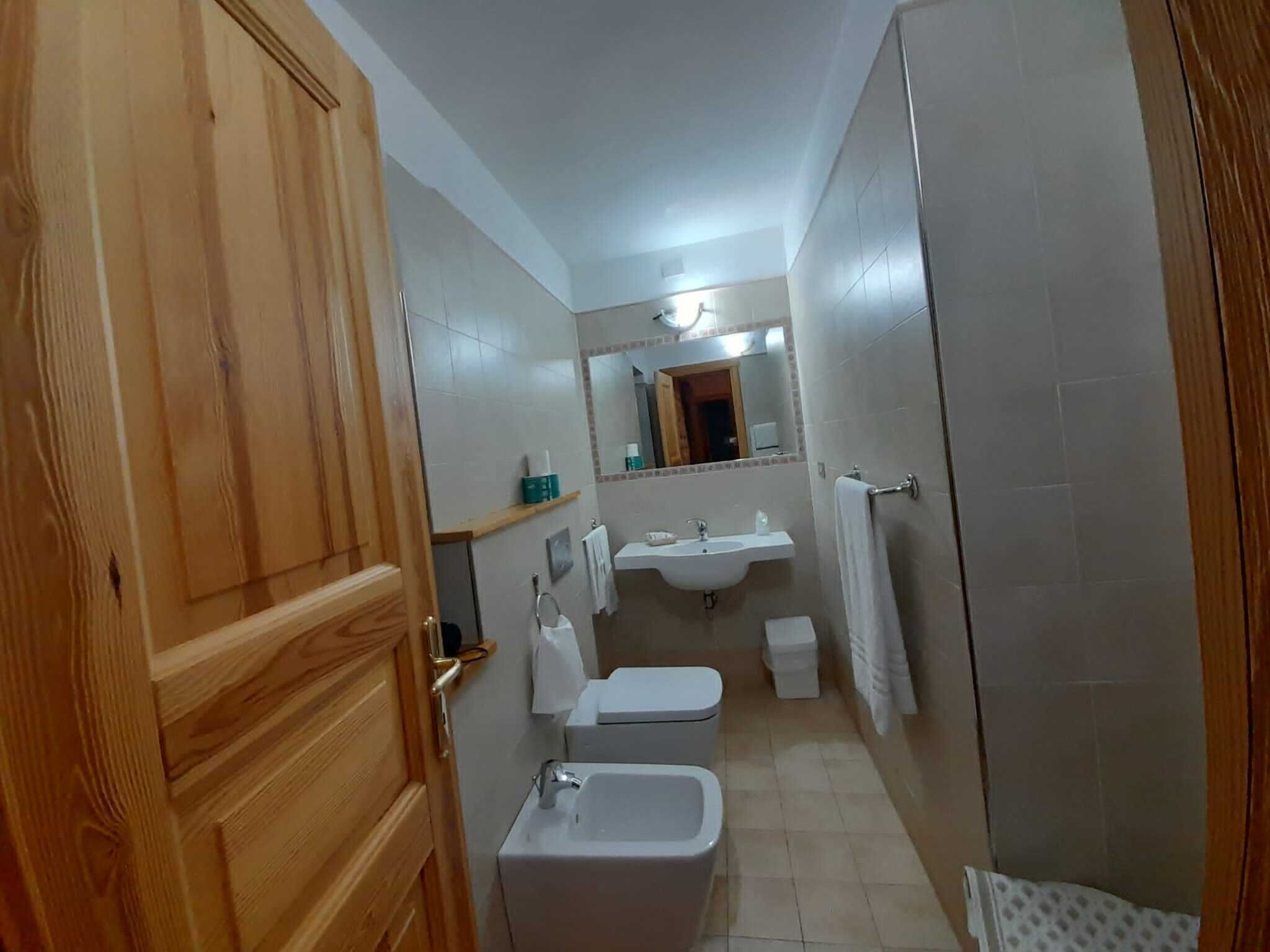 Un baño pequeño con puerta de madera, un lavabo, un inodoro y zona de ducha.