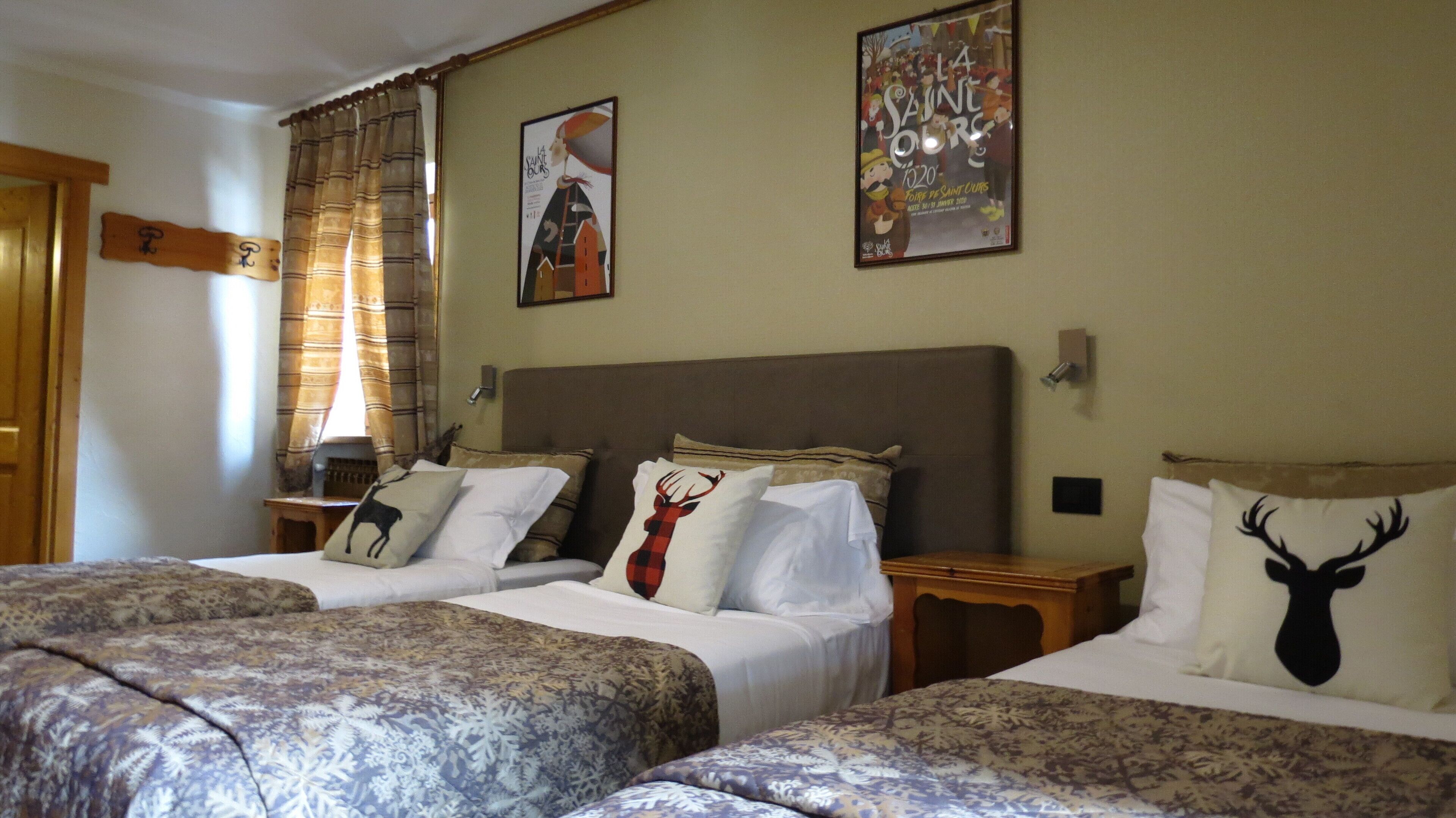 Camera d'albergo con due letti, ognuno con biancheria a motivi decorativi e cuscini ornamentali, una grande testiera e un quadro appeso al muro.