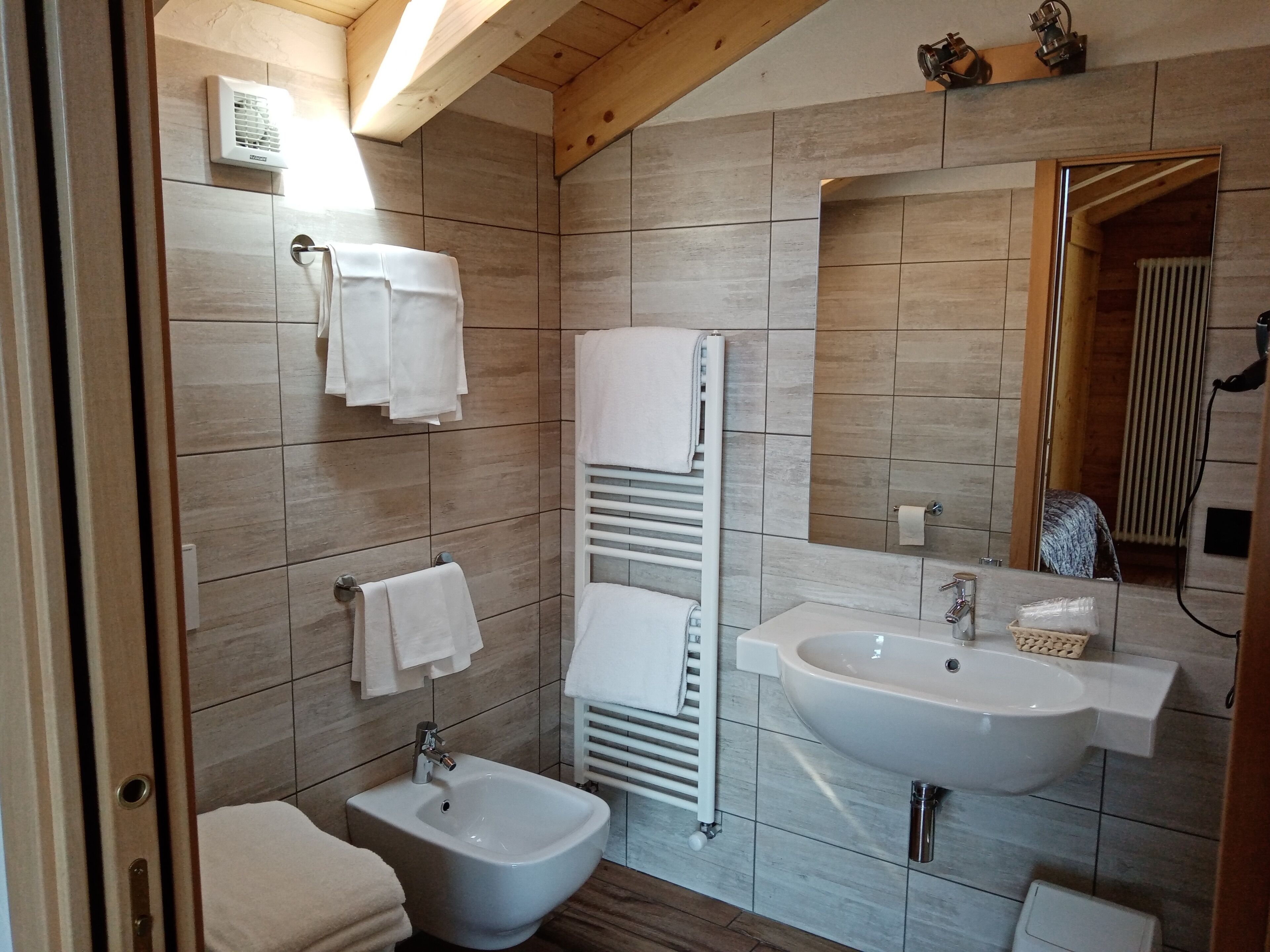 A modern bathroom with a bidet, sink, and towel racks.