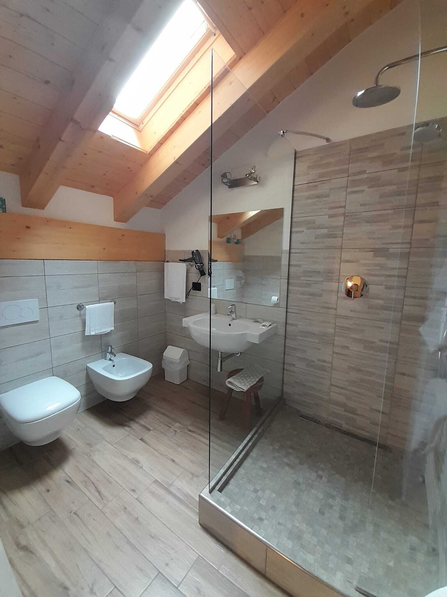 A modern bathroom with a glass-enclosed shower, a bidet, a toilet, and a sink.