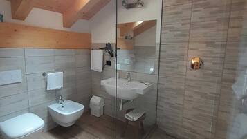 A modern bathroom with a glass-enclosed shower, a bidet, a toilet, and a sink.