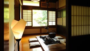Una habitación japonesa tradicional con suelo de tatami, un biombio shoji y una disposición para ceremonia del té.