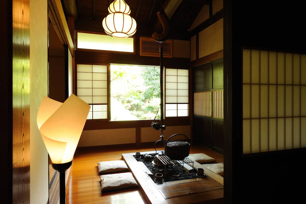 Une pièce de style japonais traditionnel, avec un sol recouvert de tatamis, un paravent shoji et un espace aménagé pour la cérémonie du thé.