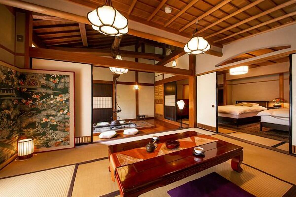 Une pièce de style japonais traditionnel, avec un sol recouvert de tatamis, une petite table en bois et un futon servant de lit.