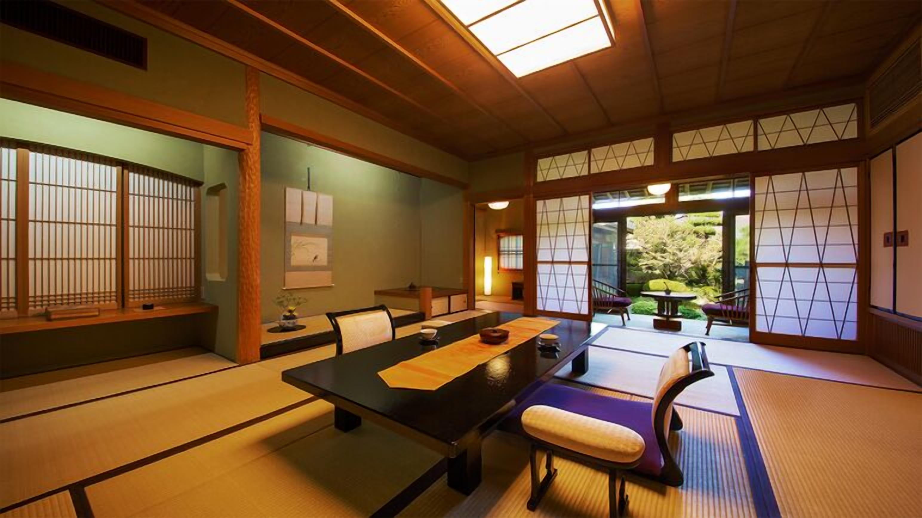 A traditional Japanese room with tatami flooring, a low table, chairs, and sliding doors.