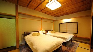 Un dormitorio de estilo japonés tradicional con dos camas, esteras de tatami y un celosía de papel.