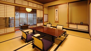 Una habitación japonesa tradicional con suelo de tatami, una mesa baja y puertas correderas shoji.