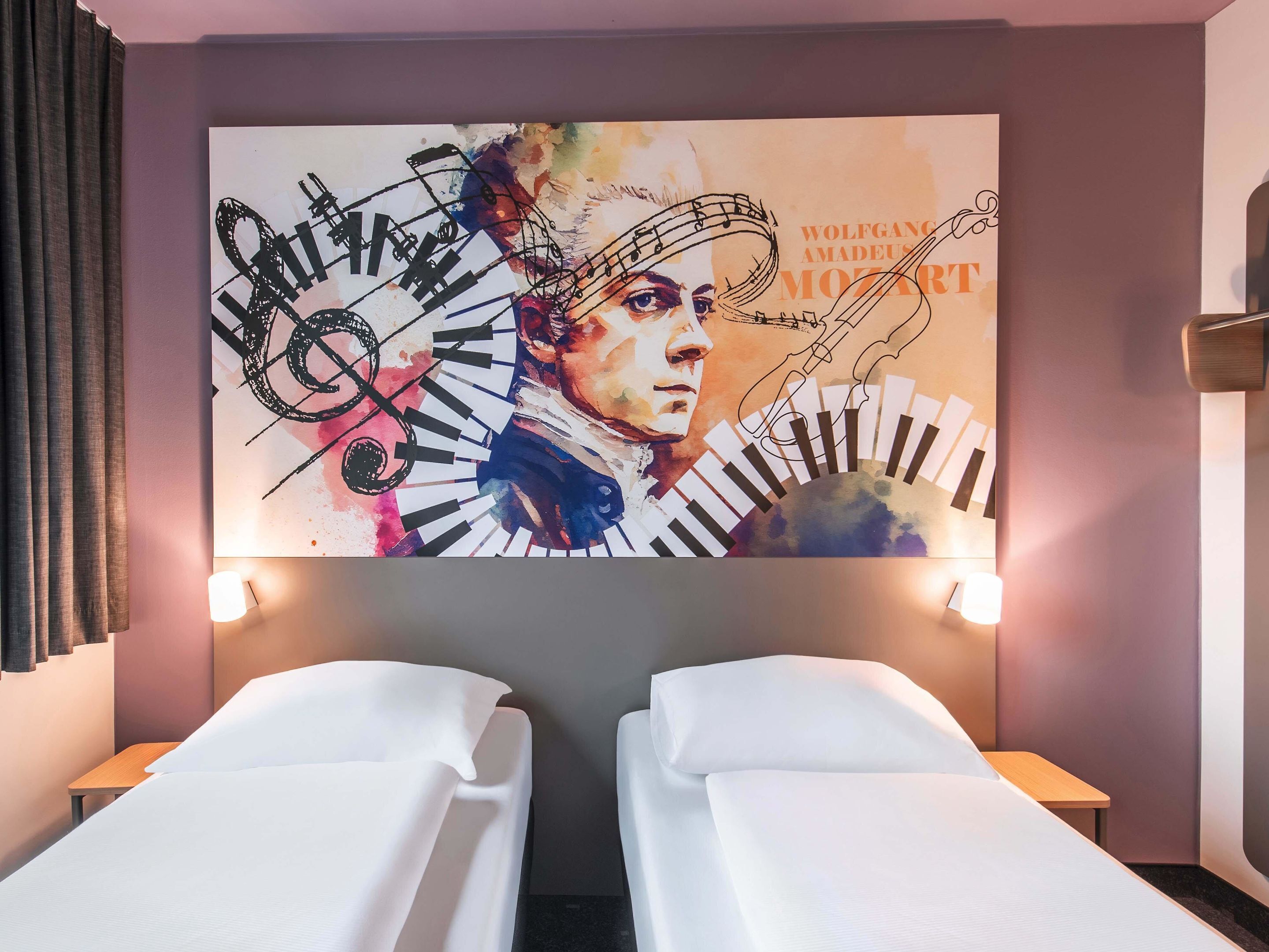 A hotel room with two single beds, a large wall mural of a musical theme, and a modern design.