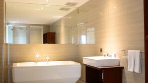 A modern bathroom with a freestanding bathtub, a vanity with a sink, and a large mirror. - The Edelweiss Ultimo Canggu (Cemagi)