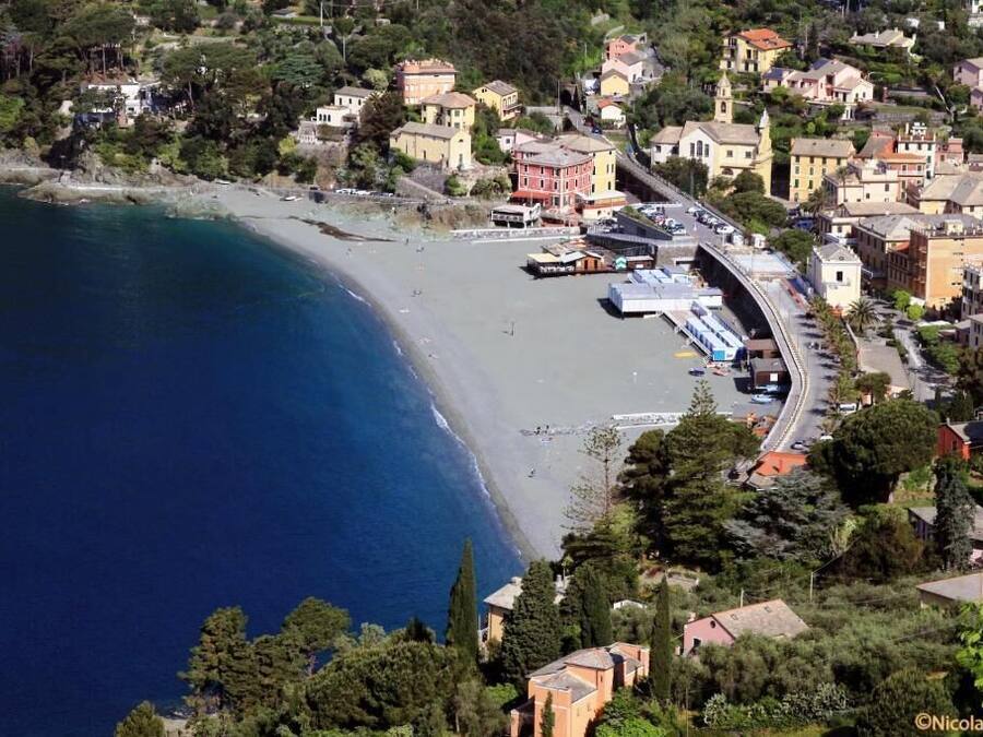 A coastal town with a beach, buildings, and a curved road.