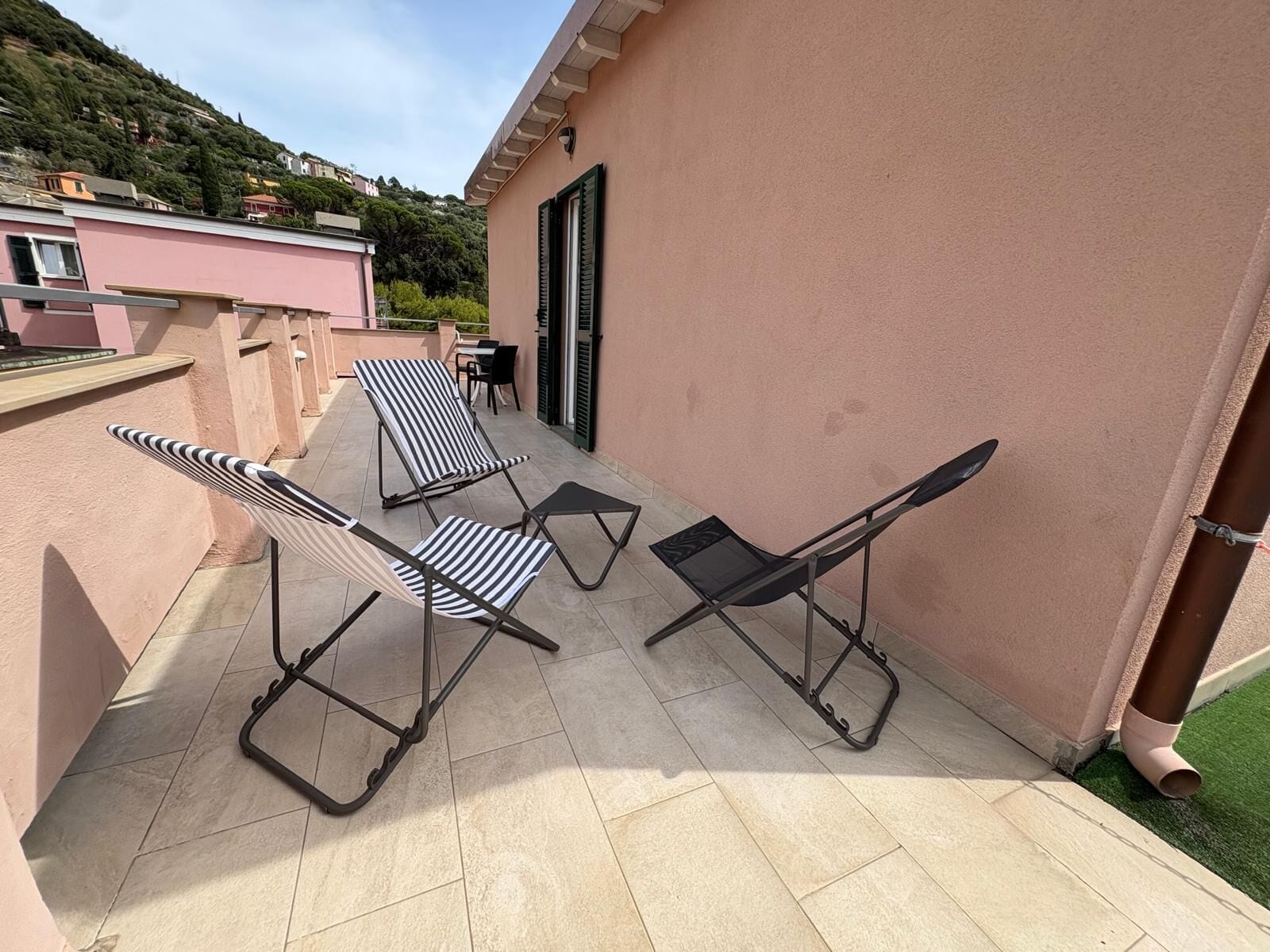 Una terraza con mobiliario exterior, una puerta y vistas a una colina.