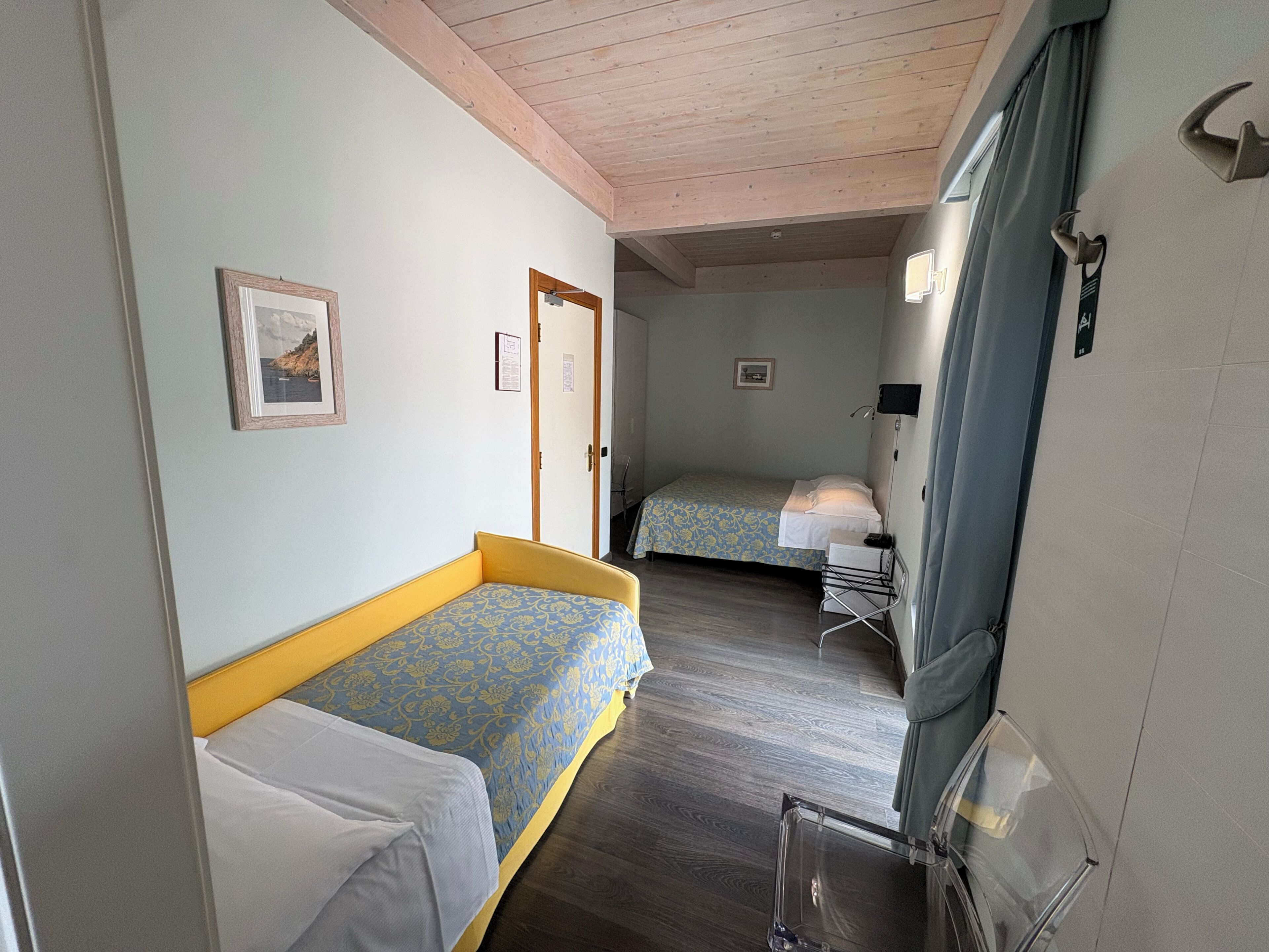A compact room with two beds, a small table, and a mirror.