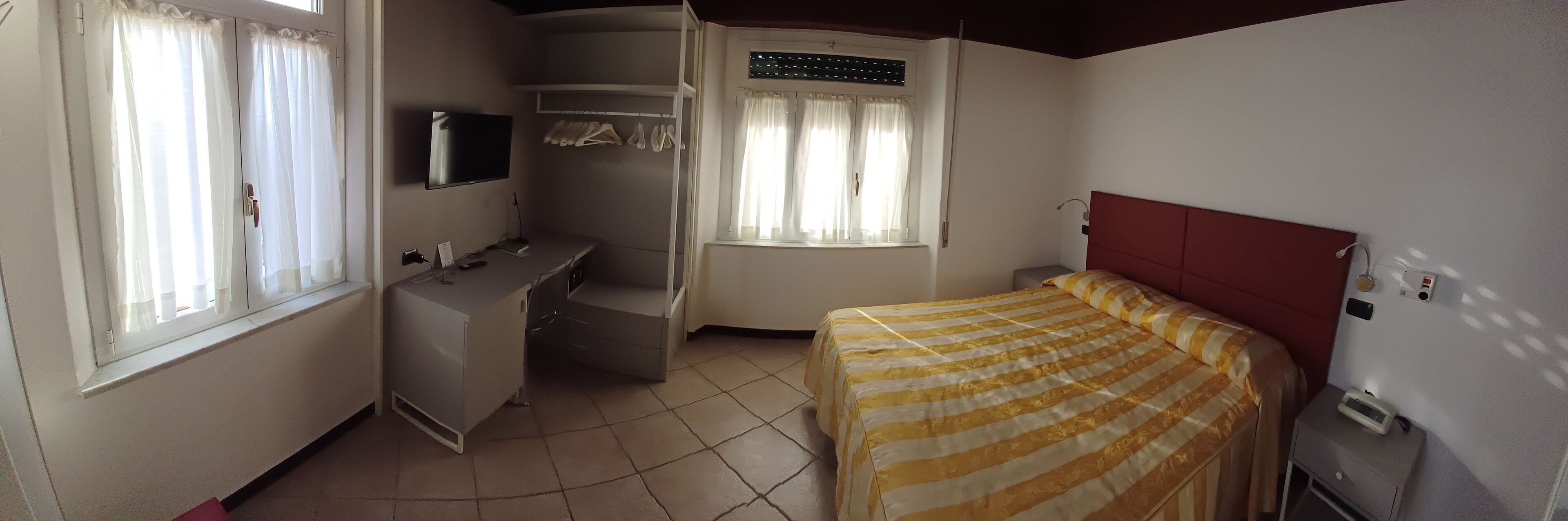 Ett kompakt hotellrum med en säng, ett skrivbord, en TV och en garderob.