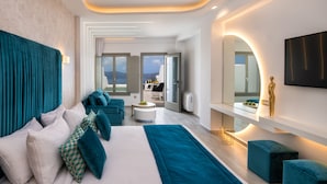 Une chambre d’hôtel moderne avec un grand lit, une literie aux couleurs turquoise et blanche, une table basse ronde et une vue sur la mer par de grandes fenêtres.
